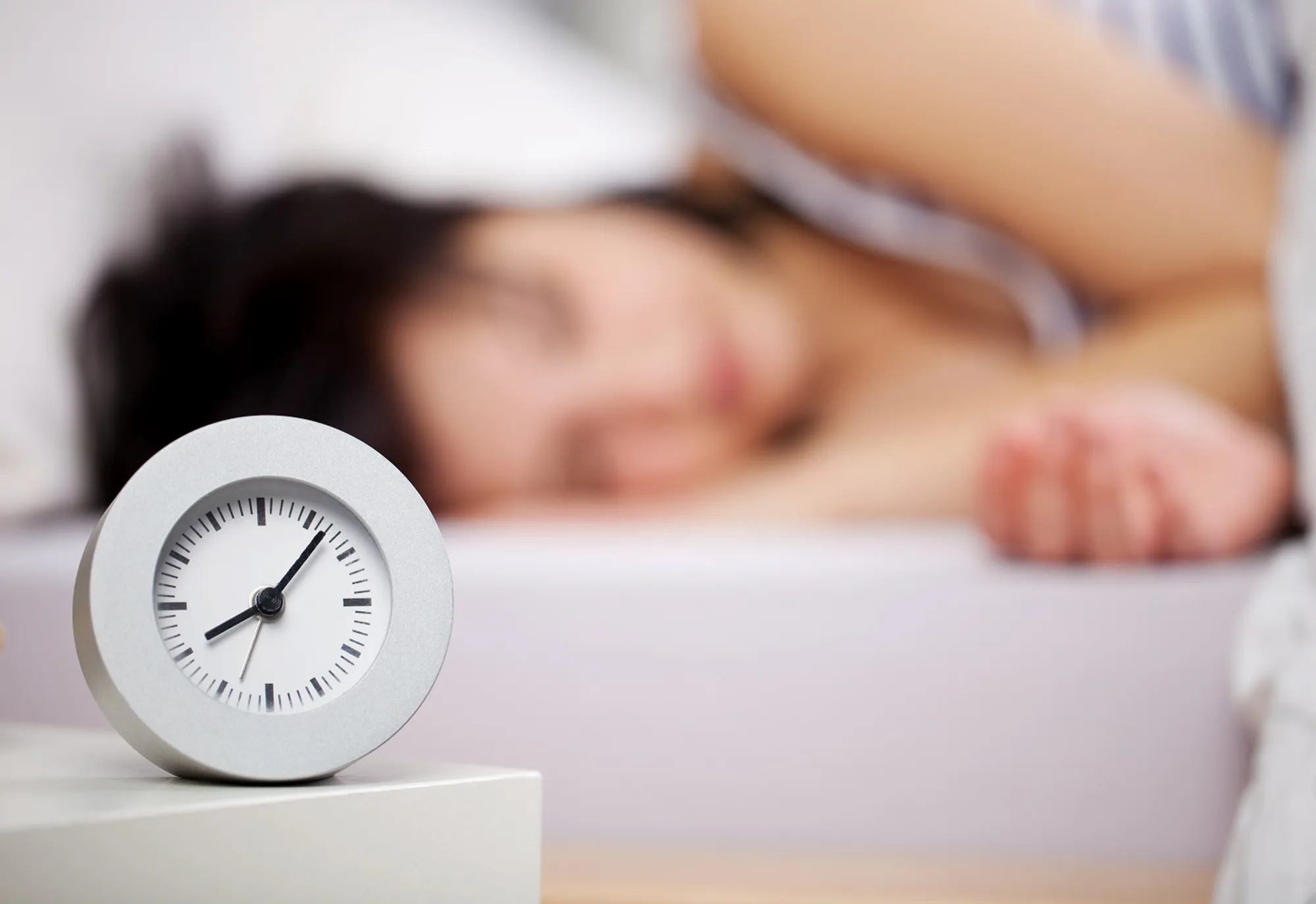 En person som sover med en klokke på nattbordet
