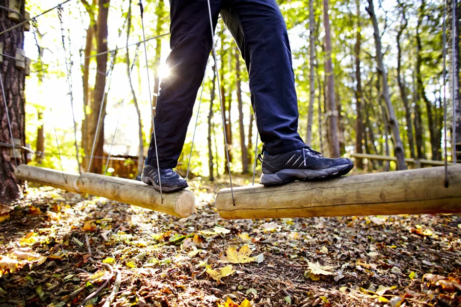 Nærbilde av at en person balanserer på en stokk i skogen