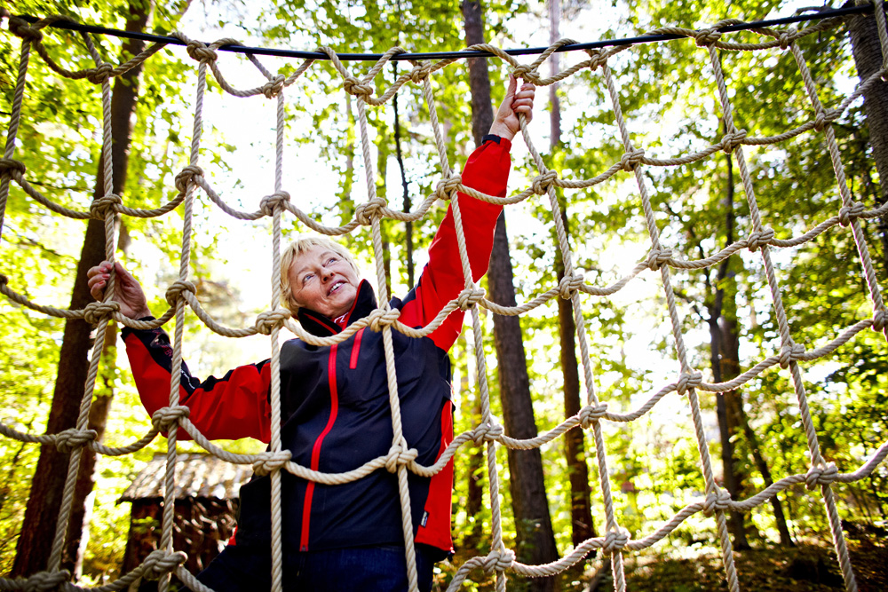 En kvinne klatrer i et klatrenett i skogen