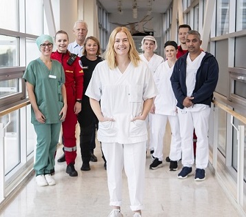 En gruppe ansatte fra ulike yrker står sammen og smiler mot kamera i en gang