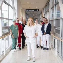 En gruppe ansatte fra ulike yrker står sammen og smiler mot kamera i en gang