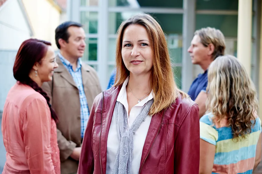 En kvinne står foran en gruppe mennesker ute