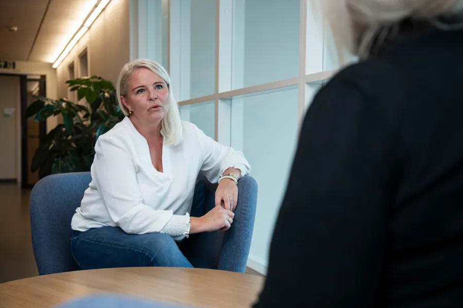 En kvinne snakker med en kvinne man ser bakhodet til