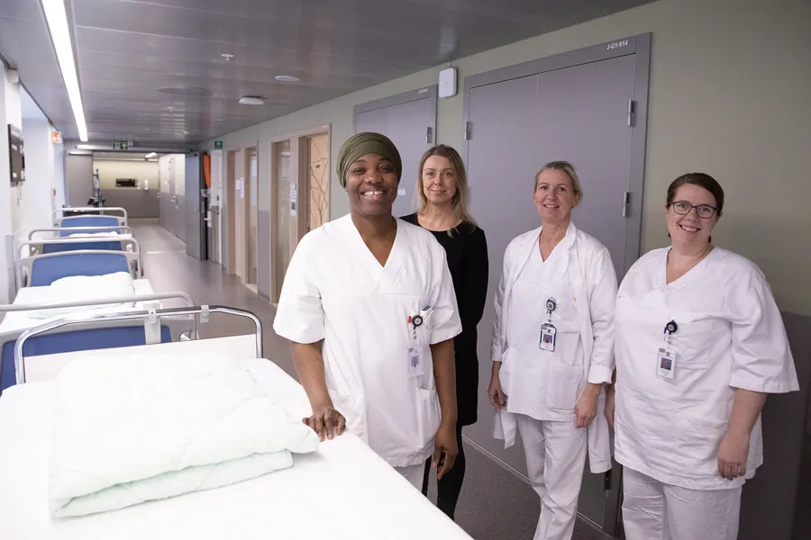 En gruppe mennesker i hvite laboratoriefrakker som står ved siden av en seng