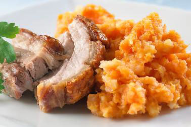 Serveringsfat med saftige skiver av stekt kjøtt ved siden av en porsjon rotmos laget av gulrøtter og poteter.