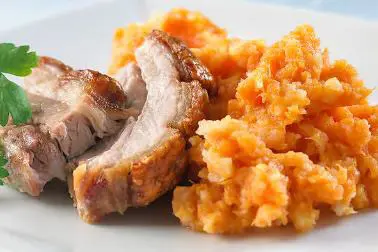 Serveringsfat med saftige skiver av stekt kjøtt ved siden av en porsjon rotmos laget av gulrøtter og poteter.