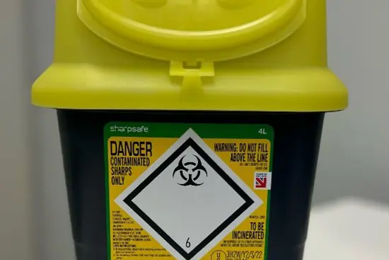 En gul kanylebøtte med en etikett