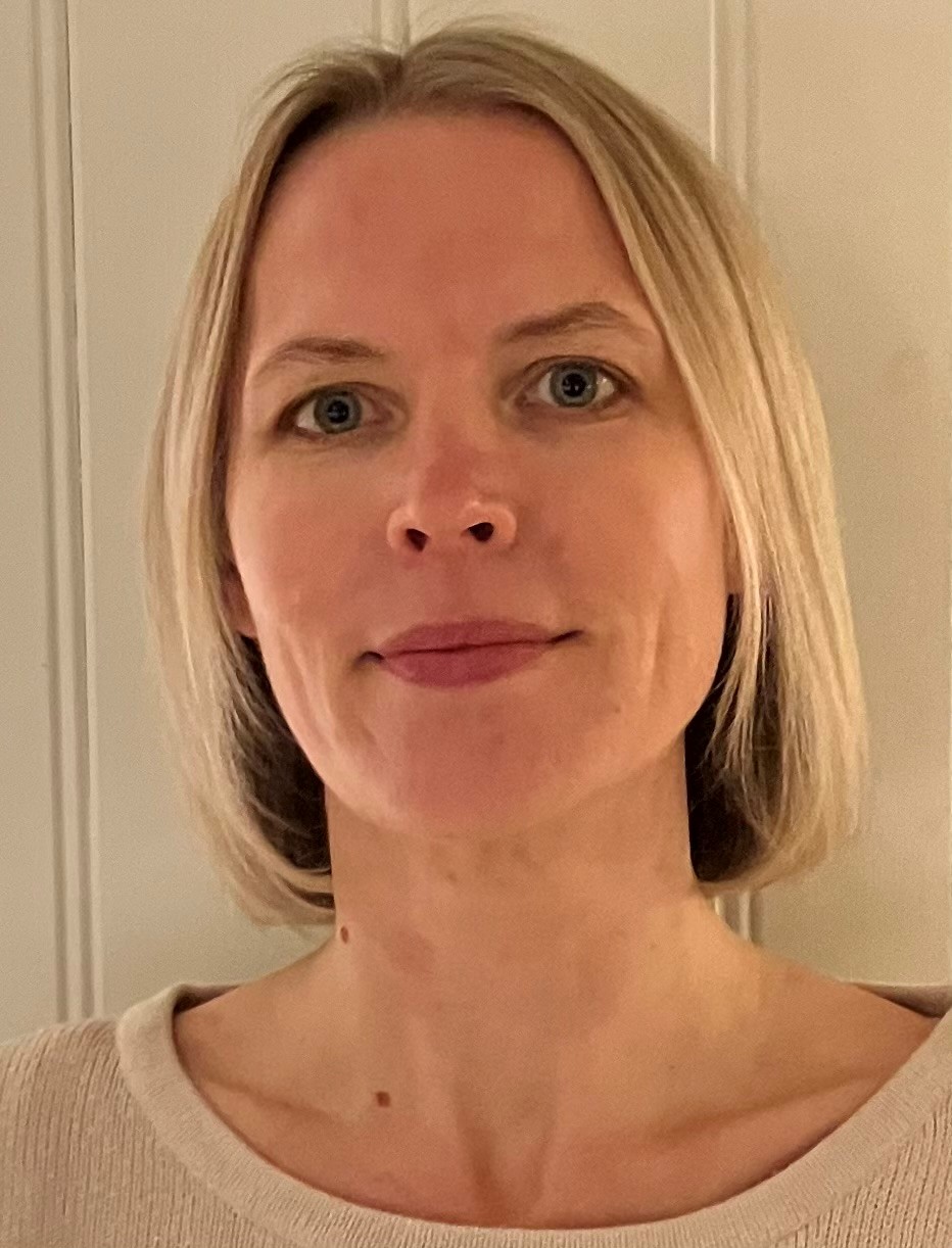 Portrettfoto av en voksen person med lyst, skulderlangt hår, iført lys genser, fotografert innendørs mot en lys bakgrunn.