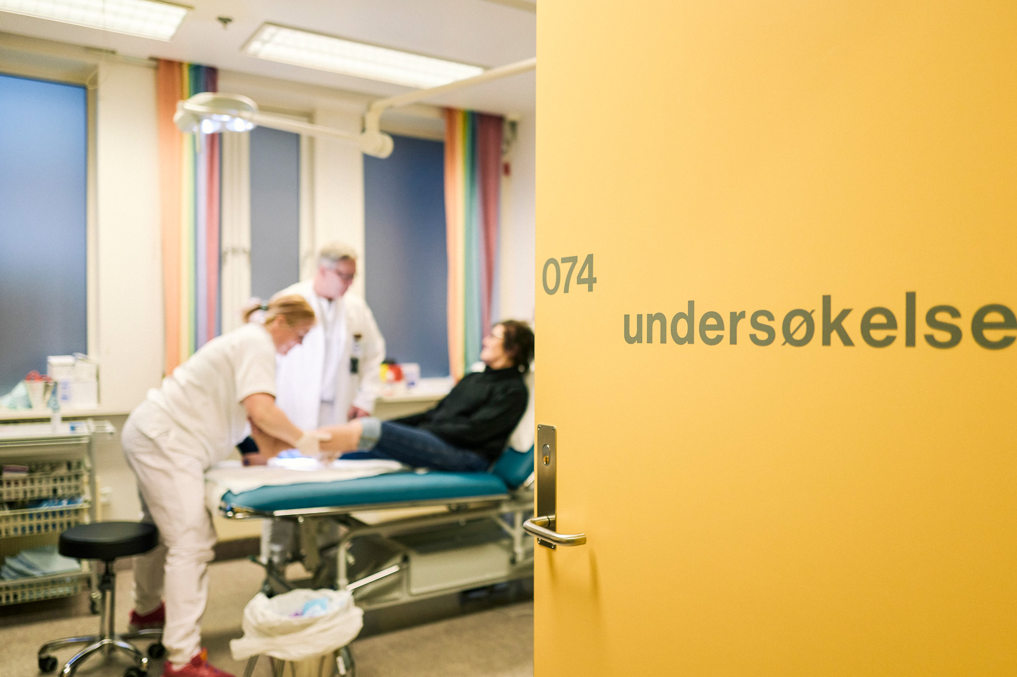 Helsepersonell og en pasient inne på et undersøkelsesrom