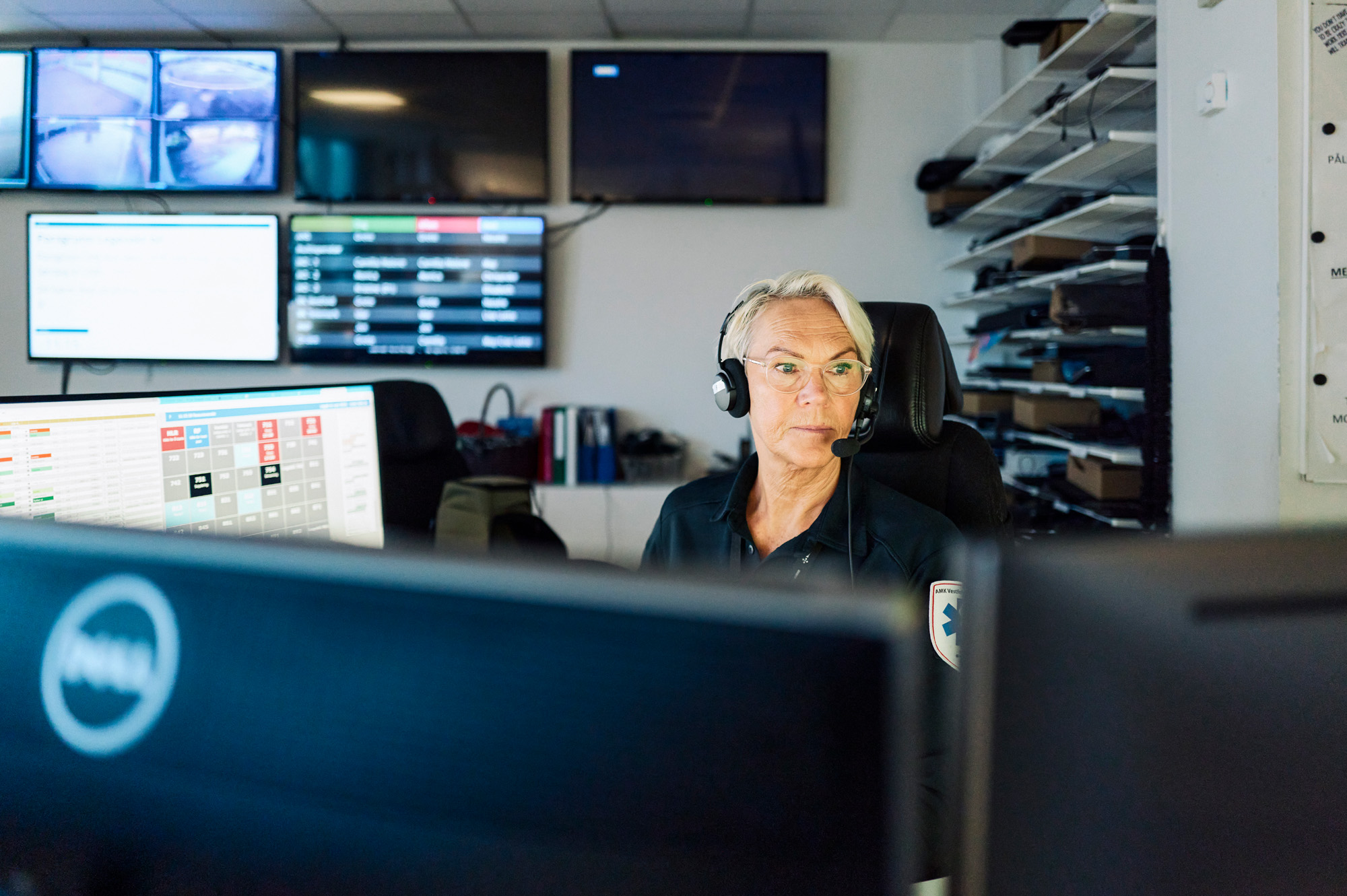 AMK-operatør med headset sitter i AMK-sentralen foran PC-skjermer