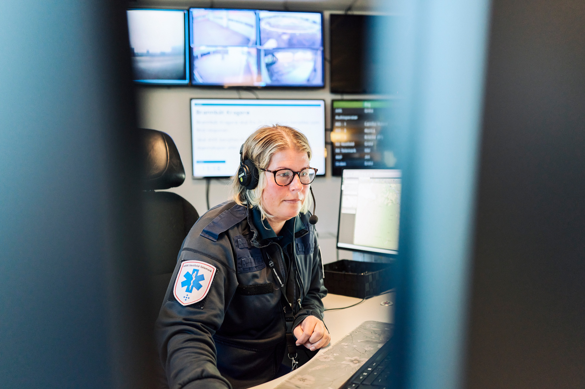 AMK-operatør med headset sitter i AMK-sentralen foran PC-skjermer