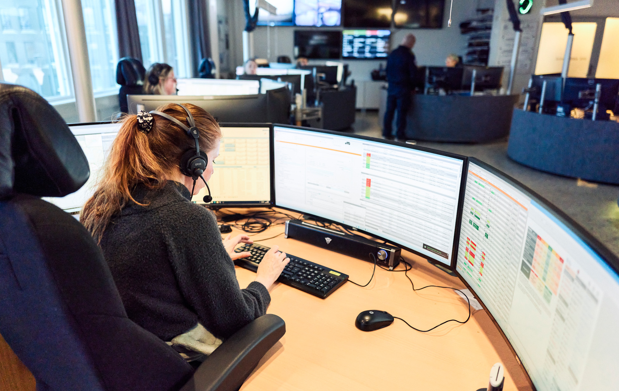 AMK-operatør med headset sitter i AMK-sentralen foran PC-skjermer