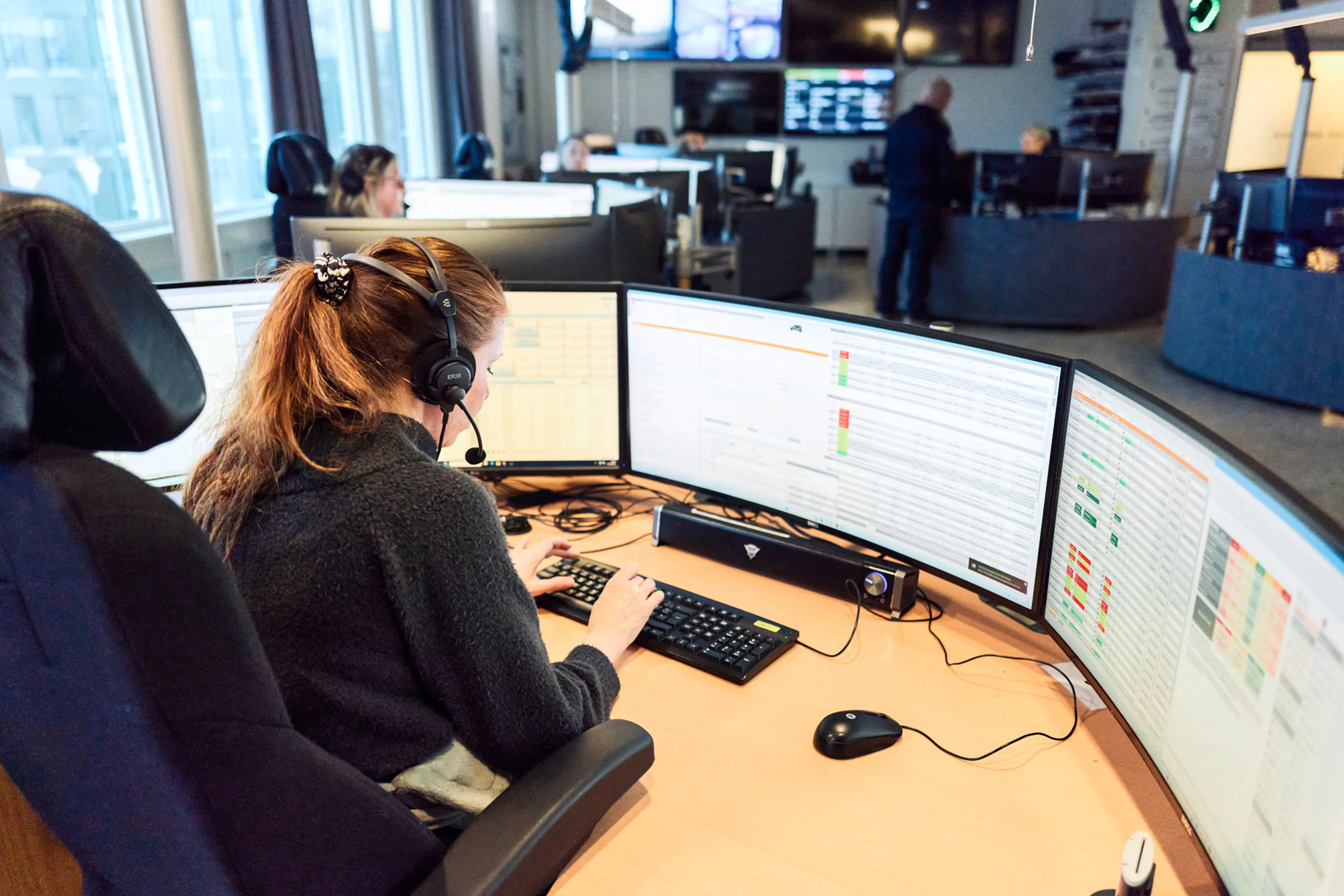 AMK-operatør med headset sitter i AMK-sentralen foran PC-skjermer