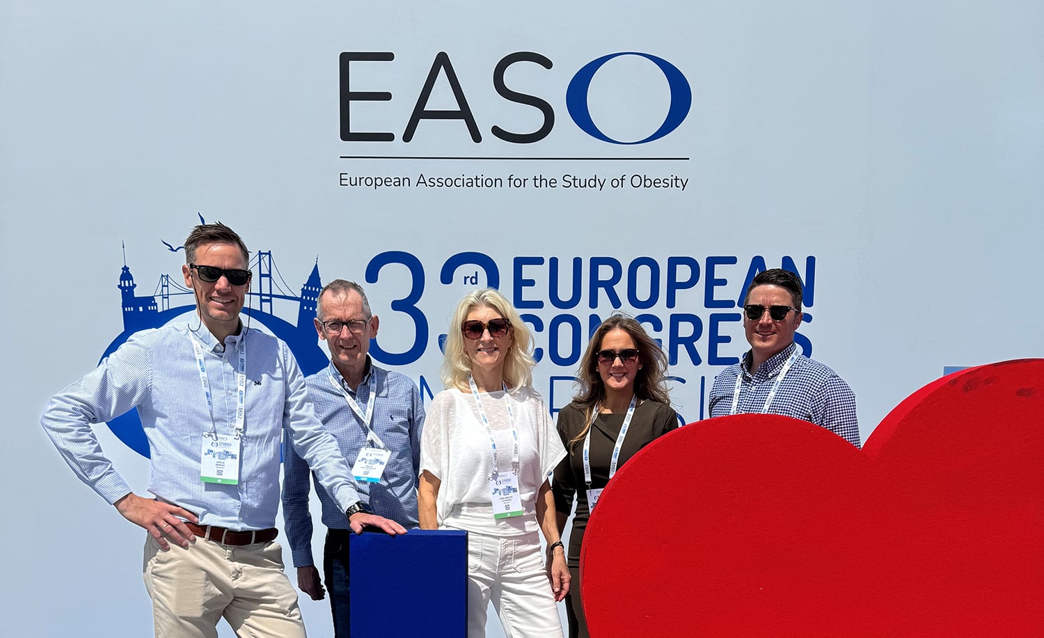 Fem personer med konferansebadger står foran en stor EASO‑bakvegg under den europeiske fedmekongressen. Bakgrunnen viser grafiske elementer og kongresslogo.