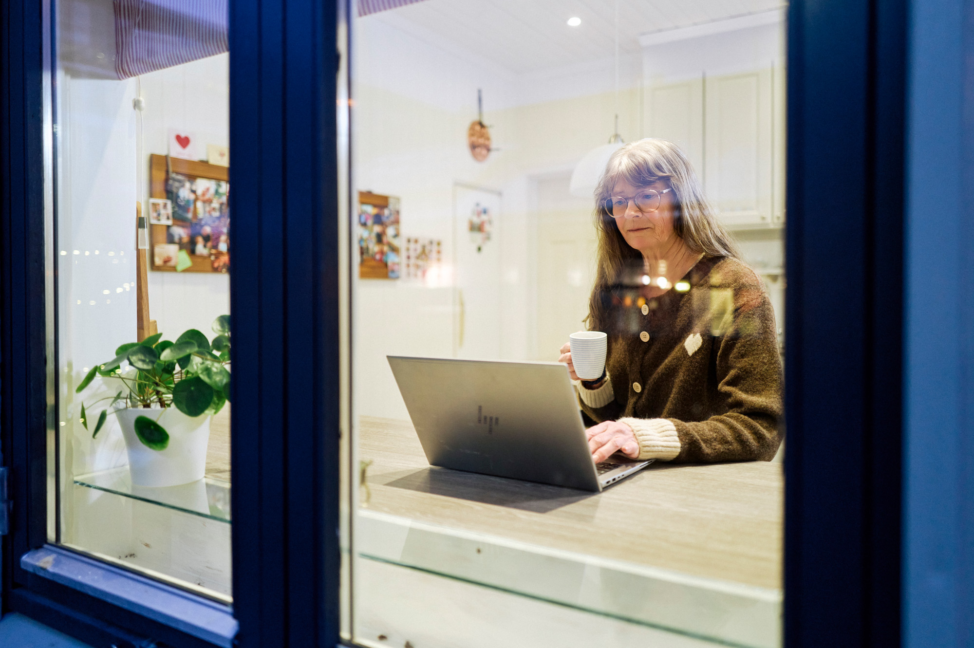 En person som sitter ved et skrivebord med en laptop og en kopp