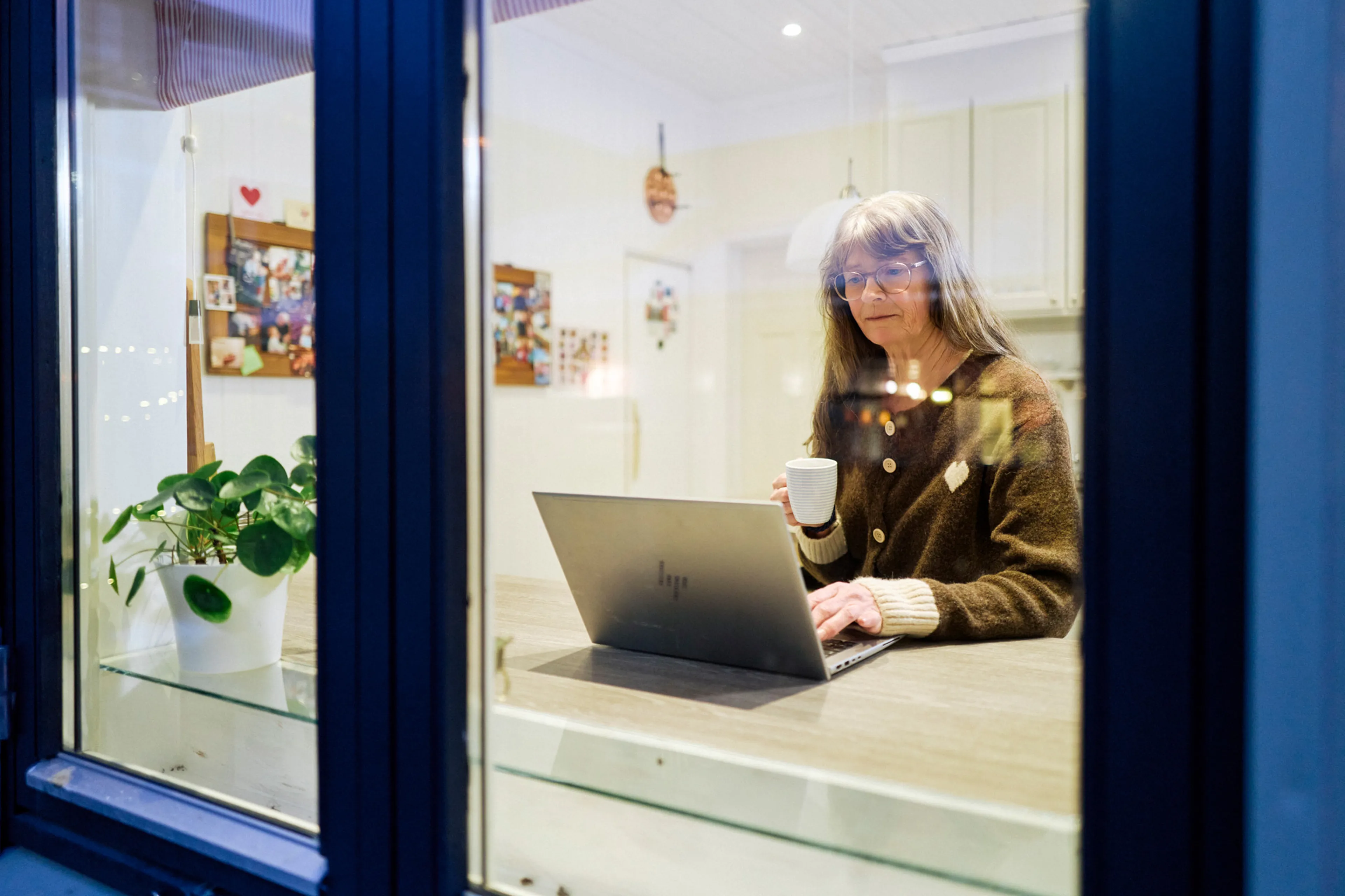 En person som sitter ved et skrivebord med en laptop og en kopp