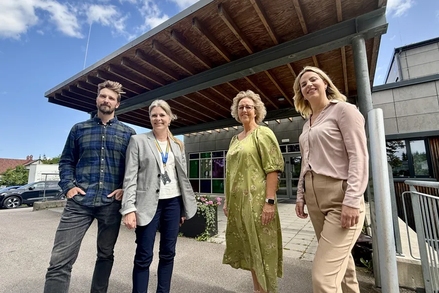 En gruppe mennesker som poserer for et bilde ute i sola foran et offentlig bygg