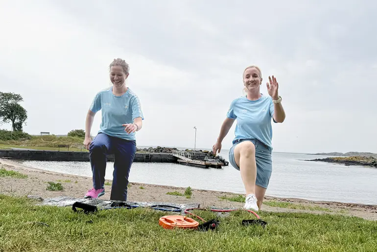 Et par kvinner som poserer for et bilde ved siden av en vannmasse