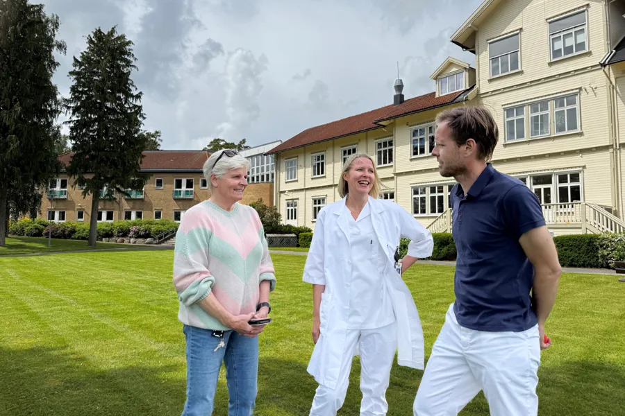 Tre personer står utenfor et gammelt bygg
