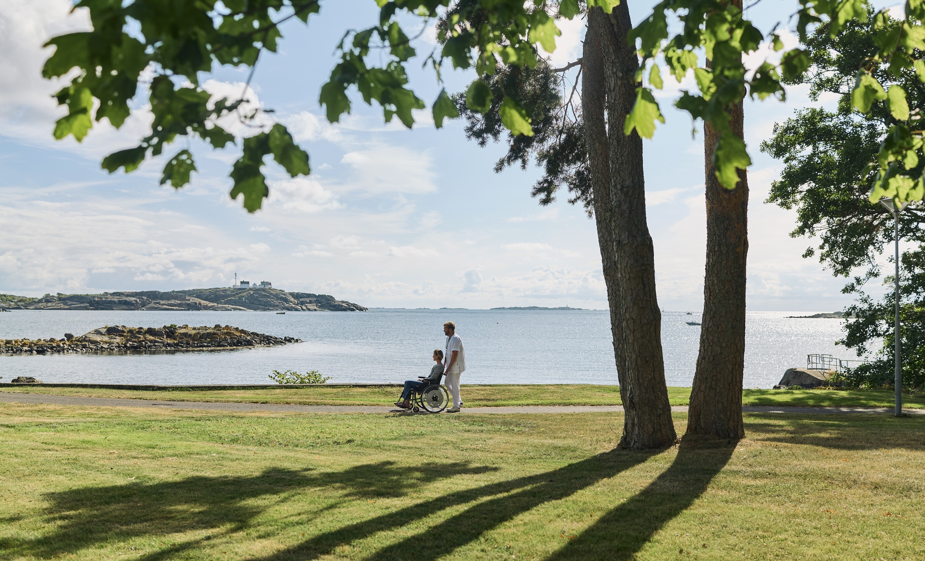 En person og et barn som går på en sti ved et vann