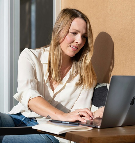 En kvinne som sitter ved et bord med en bærbar datamaskin