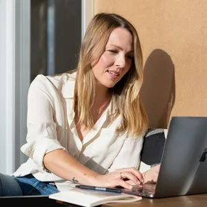 En kvinne som sitter ved et bord med en bærbar datamaskin