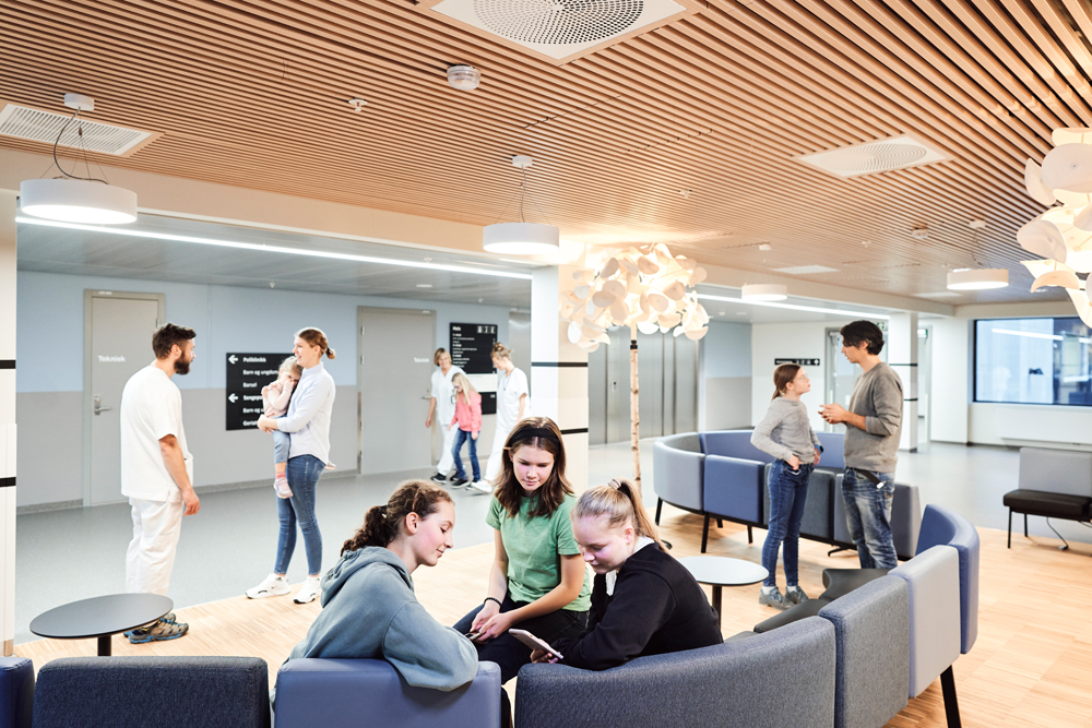 En gruppe mennesker sitter og står i et venteområde