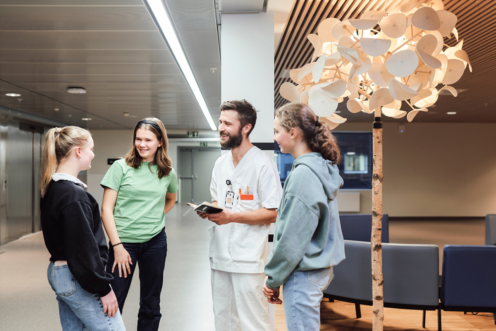 Tre tenåringsjenter og en sykepleier står og snakker sammen