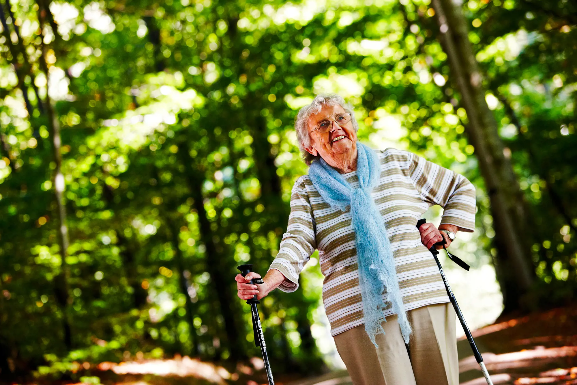 Illustrasjonsbilde av en eldre kvinne som går tur med staver i skogen
