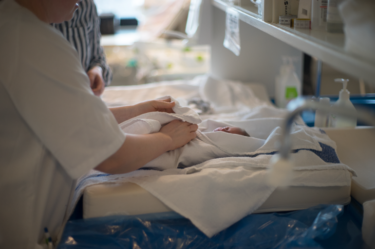 Bilde av baby som pakkes inn i håndkle