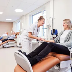 En kvinne som sitter på en stol med en mann som står ved siden av henne