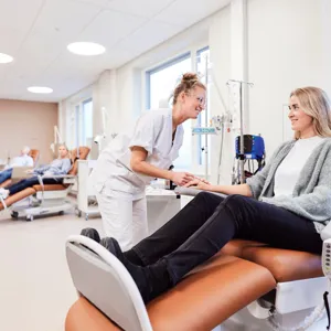 En kvinne som sitter på en stol med en mann som står ved siden av henne