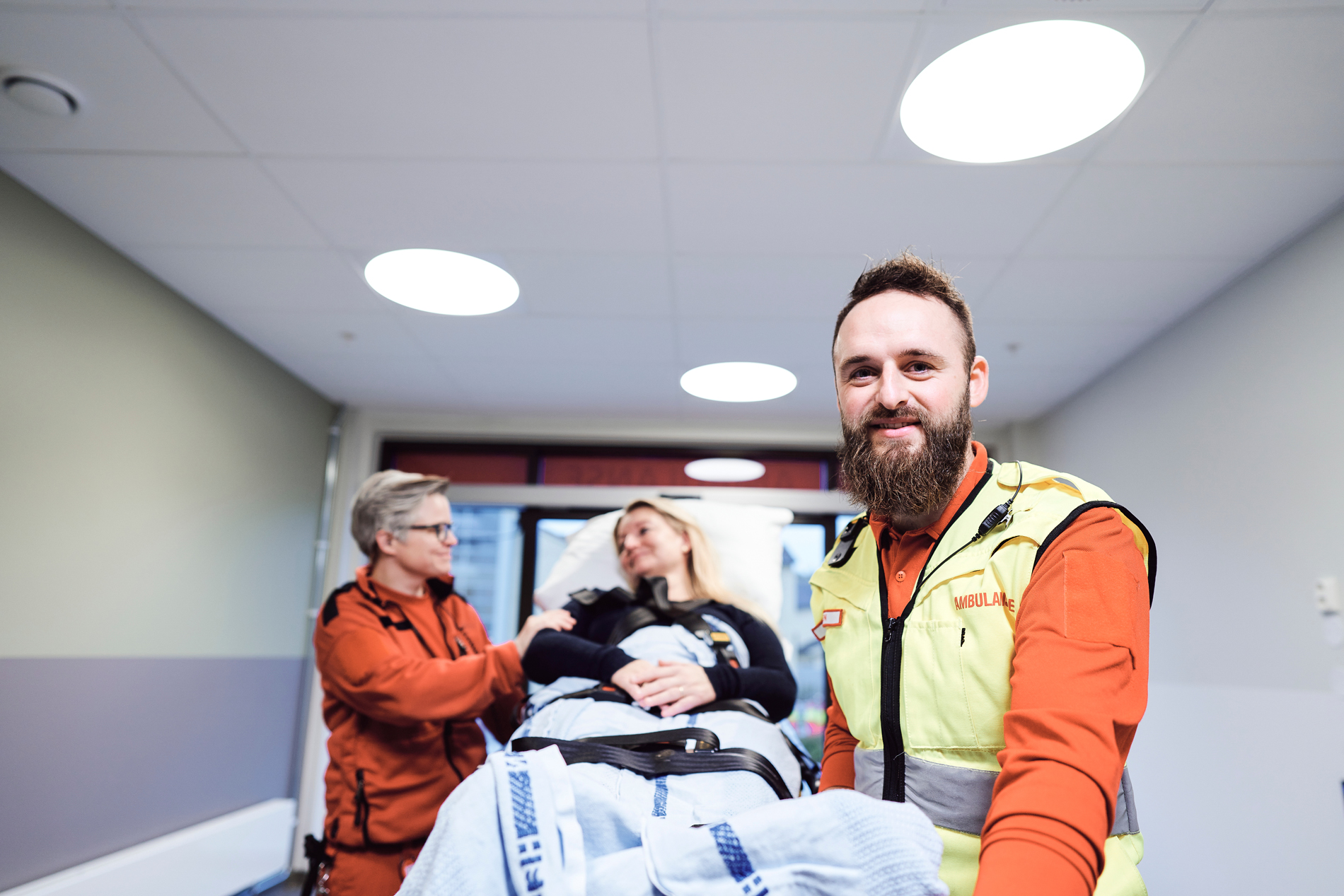 To ambulansearbeidere triller en pasient på båre