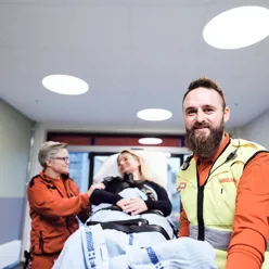 To ambulansearbeidere triller en pasient på båre