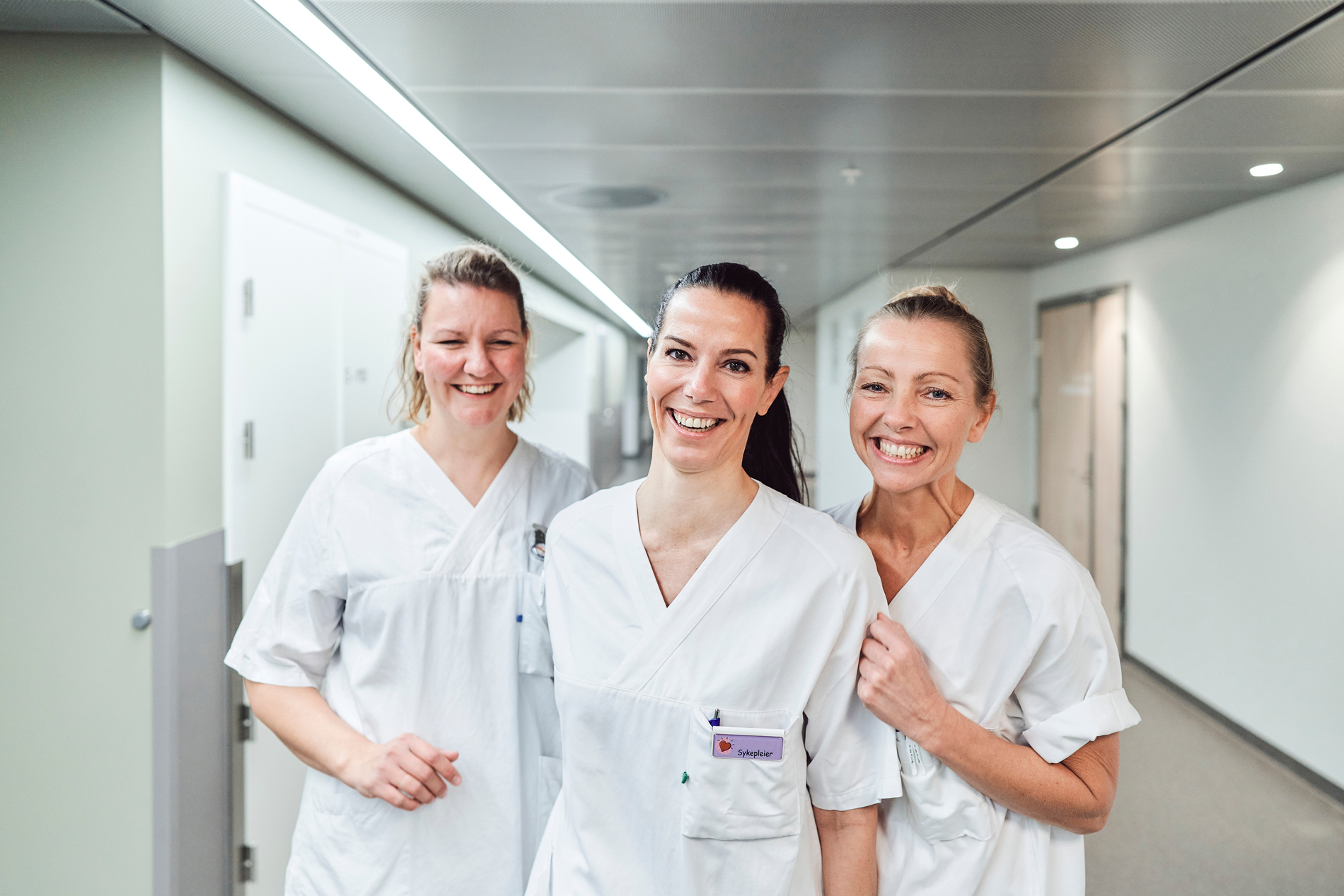 Tre smilende kvinner i hvitt arbeidsantrekk
