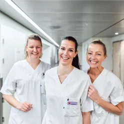 Tre smilende kvinner i hvitt arbeidsantrekk