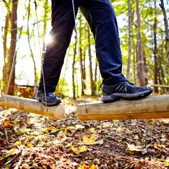 En persons ben på en trebenk i skogen