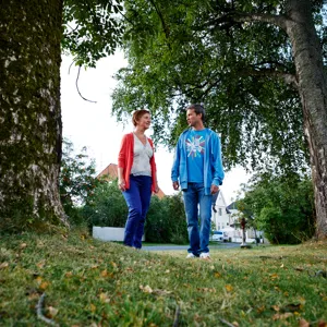 Kvinne og mann som går ute blant trær