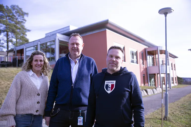 En gruppe mennesker som poserer for et bilde foran en bygning