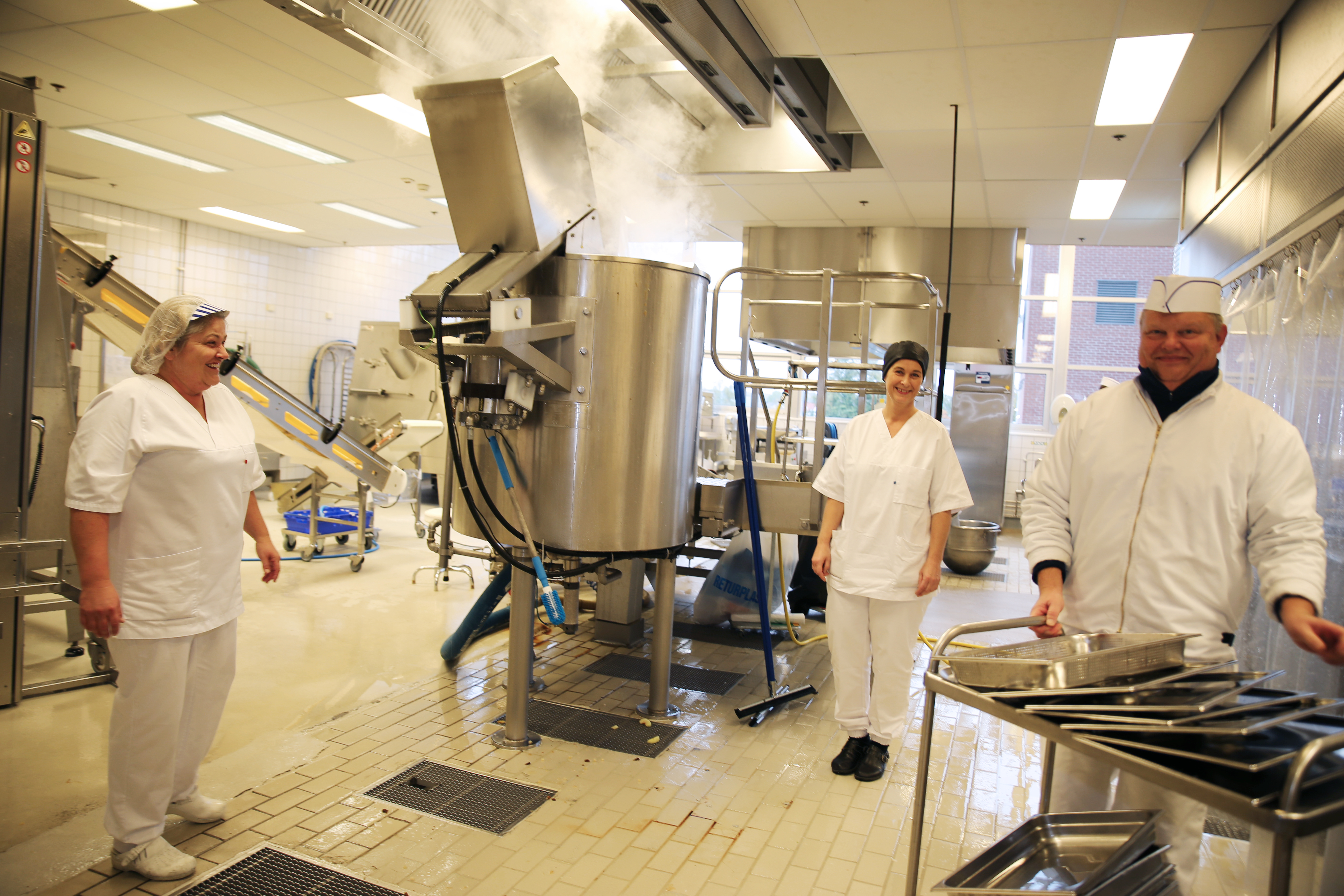 Produksjonsansvarlig Elisabeth Kettilsen, produksjonskjøkkenets leder Hege Eftedal og Bjørnar Aske står rundt den store kjelen s