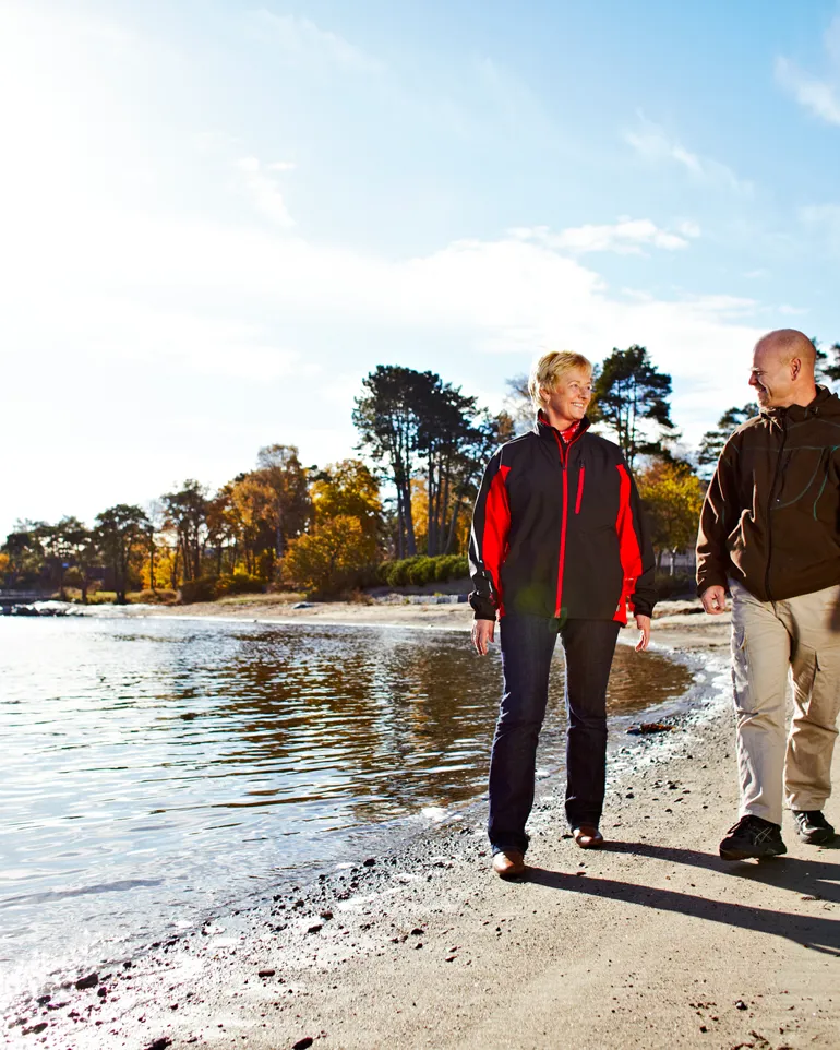 Kvinne og mann som går tur på en strand