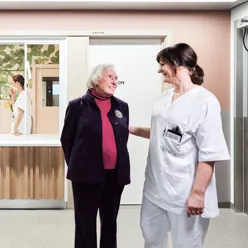 En eldre kvinne og en sykepleier i hvitt arbeidsantrekk ser på hverandre