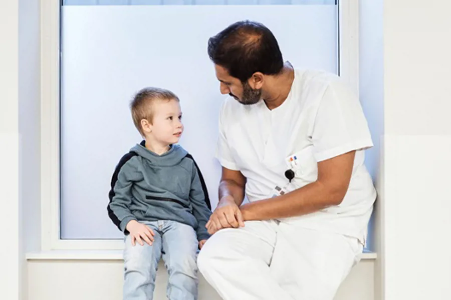 En lege sitter med et barn i en vinduskarm