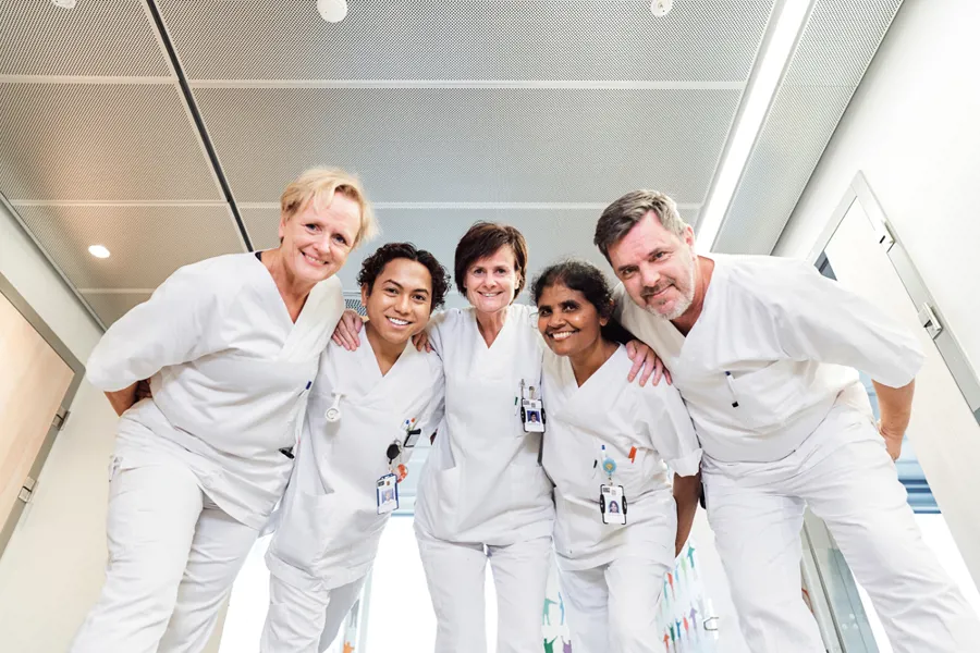 En gruppe ansatte i hvitt arbeidsantrekk står sammen og smiler