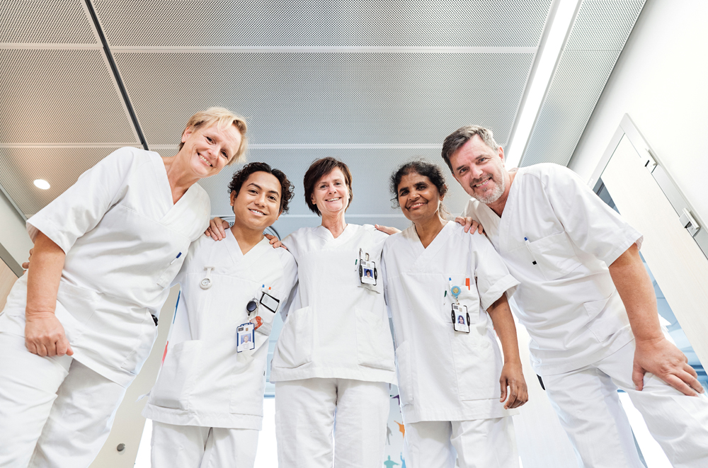En gruppe ansatte i hvitt arbeidsantrekk står sammen og smiler