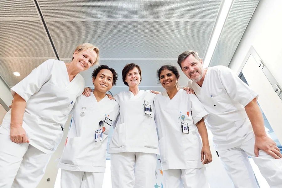 En gruppe ansatte i hvitt arbeidsantrekk står sammen og smiler