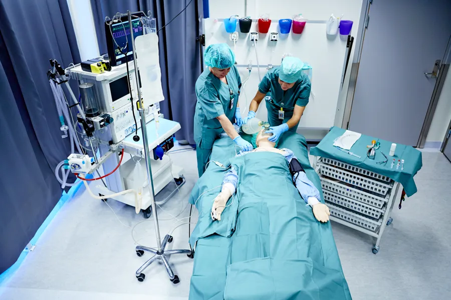 To ansatte som behandler simuleringsdukke i simuleringssenteret