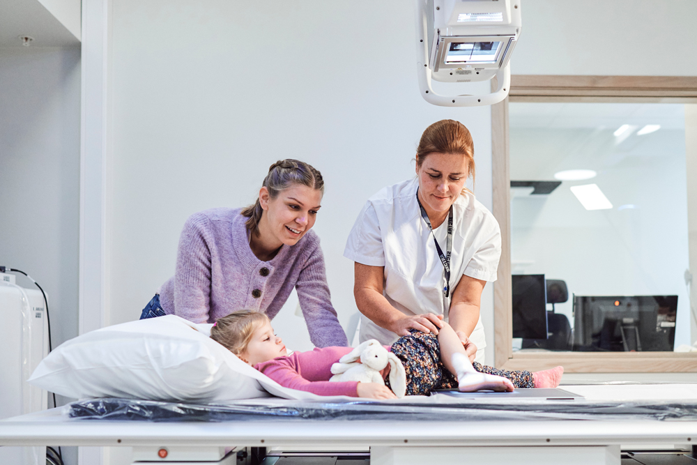 En radiograf tar røntgen av et barns fot, moren står ved siden av