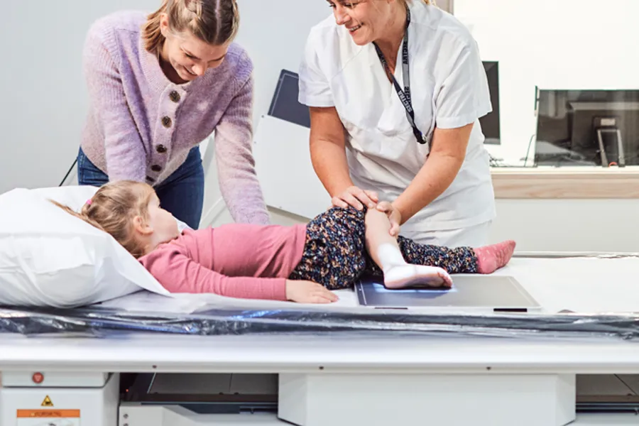 En radiograf tar røntgen av et barns fot, moren står ved siden av