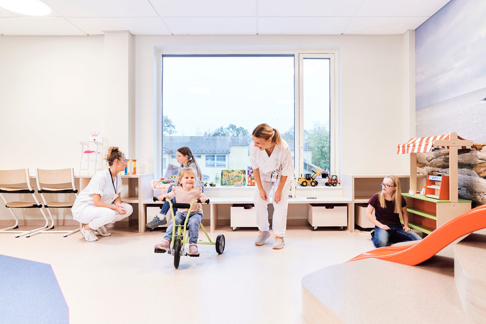 Flere barn og to sykepleiere leker i et lekerom
